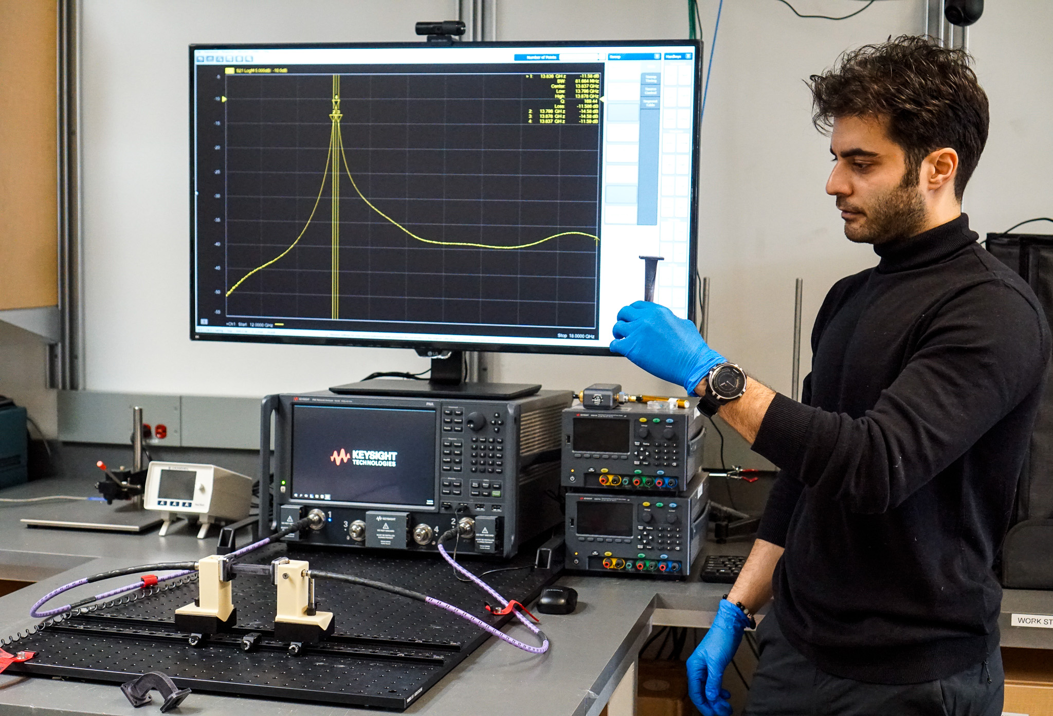 Researcher in lab holds component in front of screen