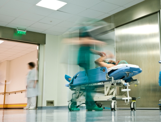 Blurred health care worker with patient on gurney in hall near hospital elevator