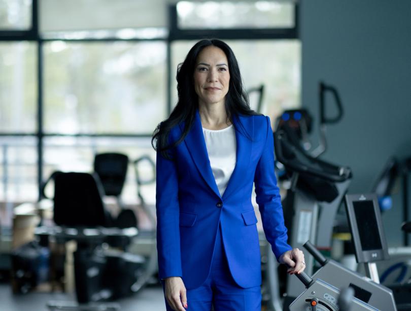 Woman in suit stands in gym with exercise machines