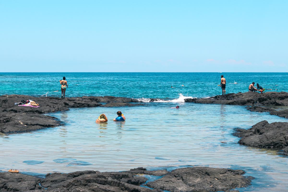 Wide-angle shot of a tide pool, with people in the distance
