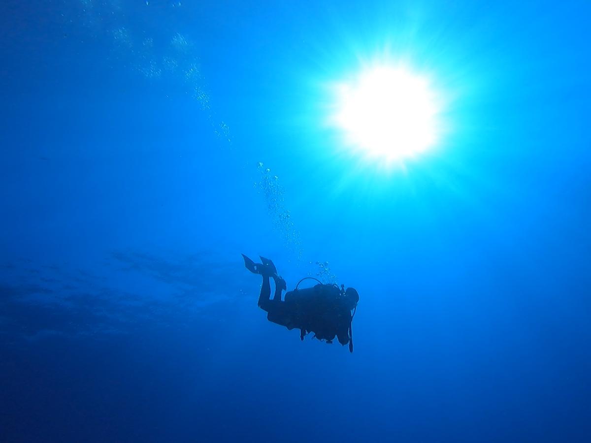 Scuba diver in the ocean, with a beam of light shining into the water