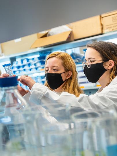 Two women with face masks on working in a lab