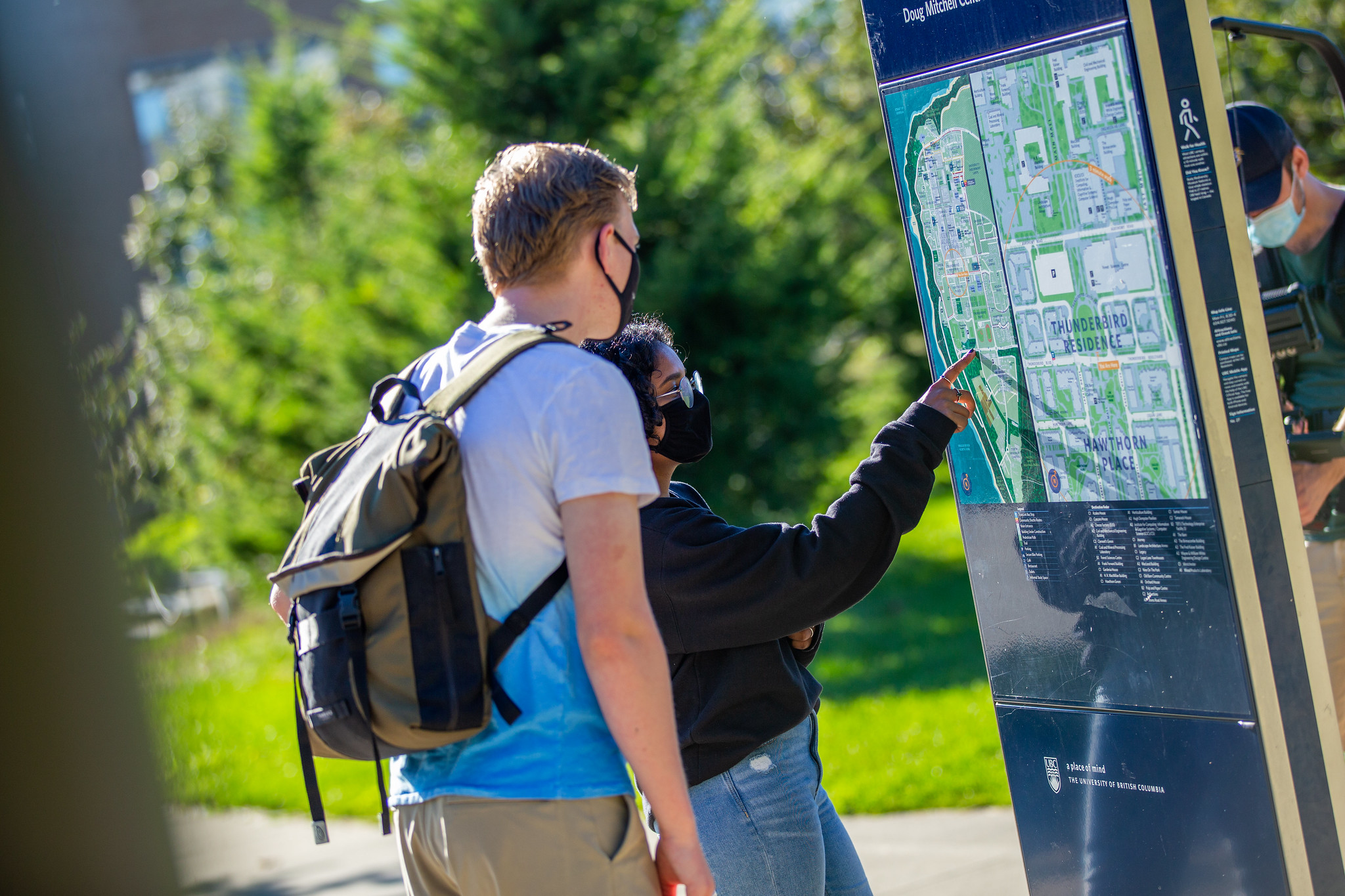 Photo of UBC students pointing to and looking at a map on campus.