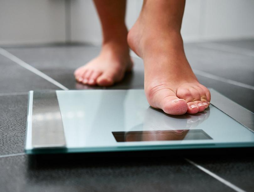 Close-up image of bare feet stepping on a digital scale