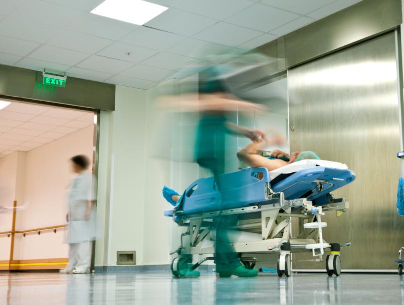 Blurred health care worker with patient on gurney in hall near hospital elevator