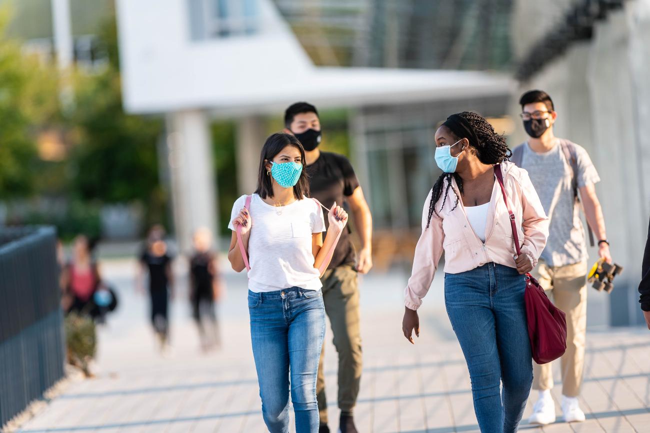 A group of UBC students with masks on walk on campus.