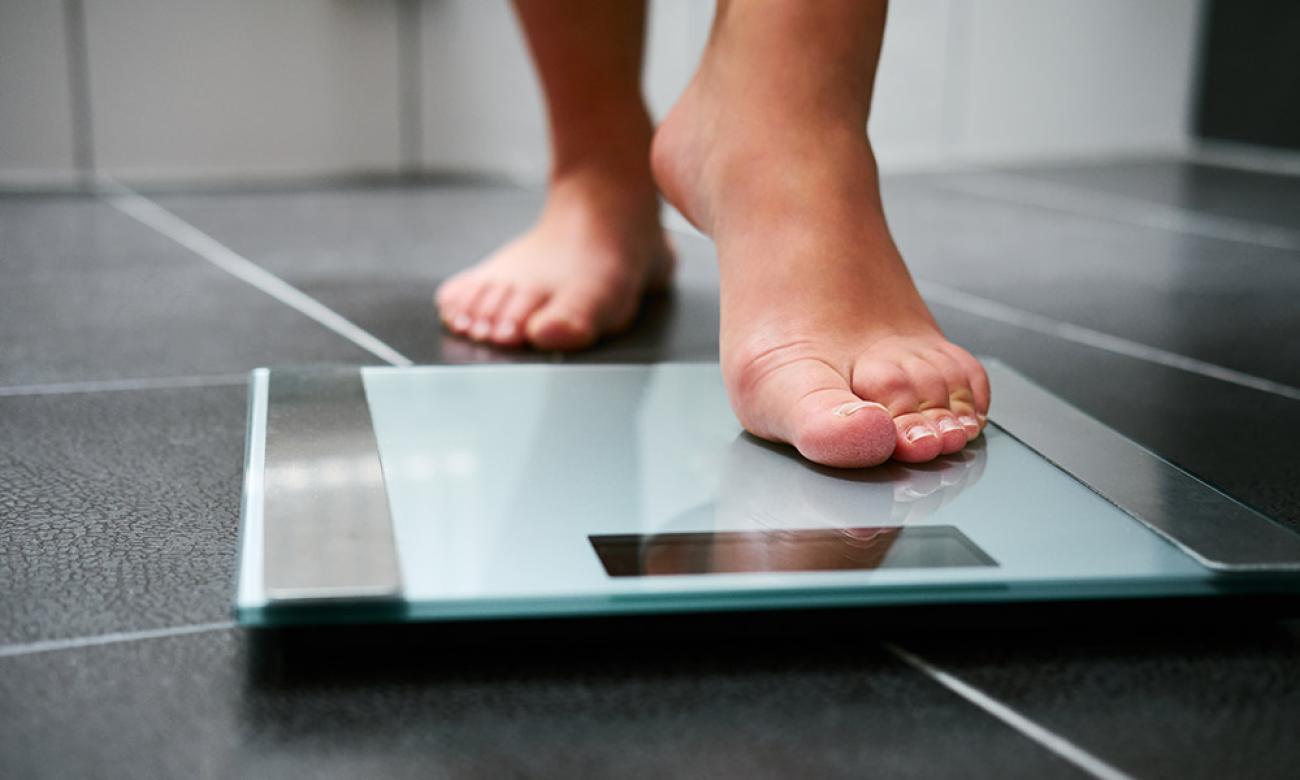 Close-up image of bare feet stepping on a digital scale