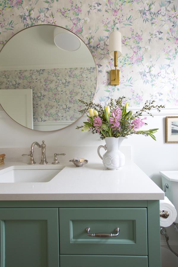 Powder room with green cabinetry and colourful wallpaper